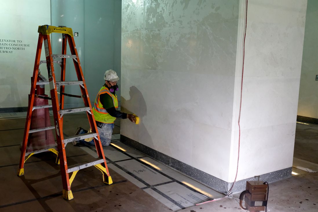 A worker tiles a wall